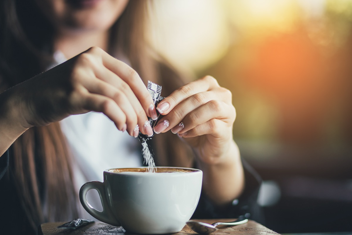 Woman adding sugar to her latte