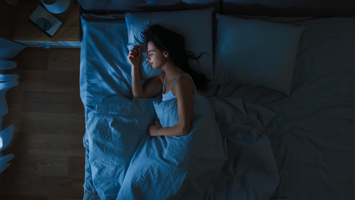 Woman happily asleep in bed at night