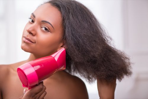 Black woman using a blow dryer on her hair