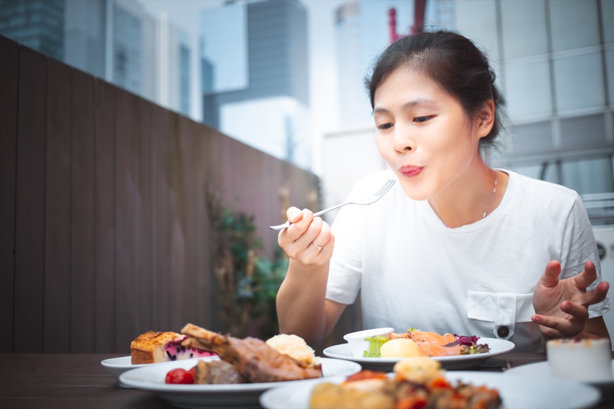 Woman eating a lot of food many plates
