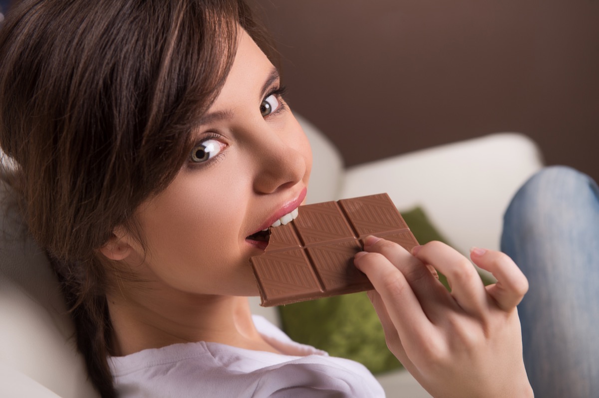 Woman happily eating chocolate bar