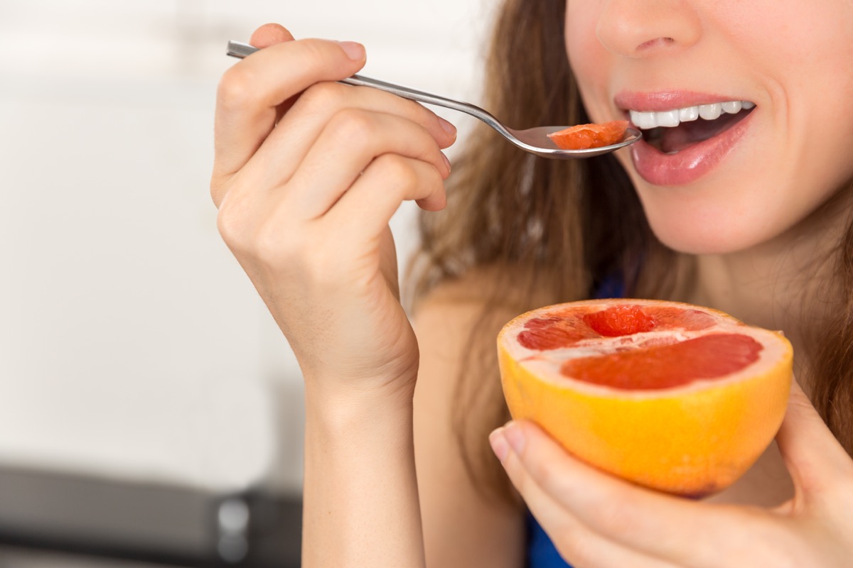 Woman about to take her first bite of a ruby grapefruit
