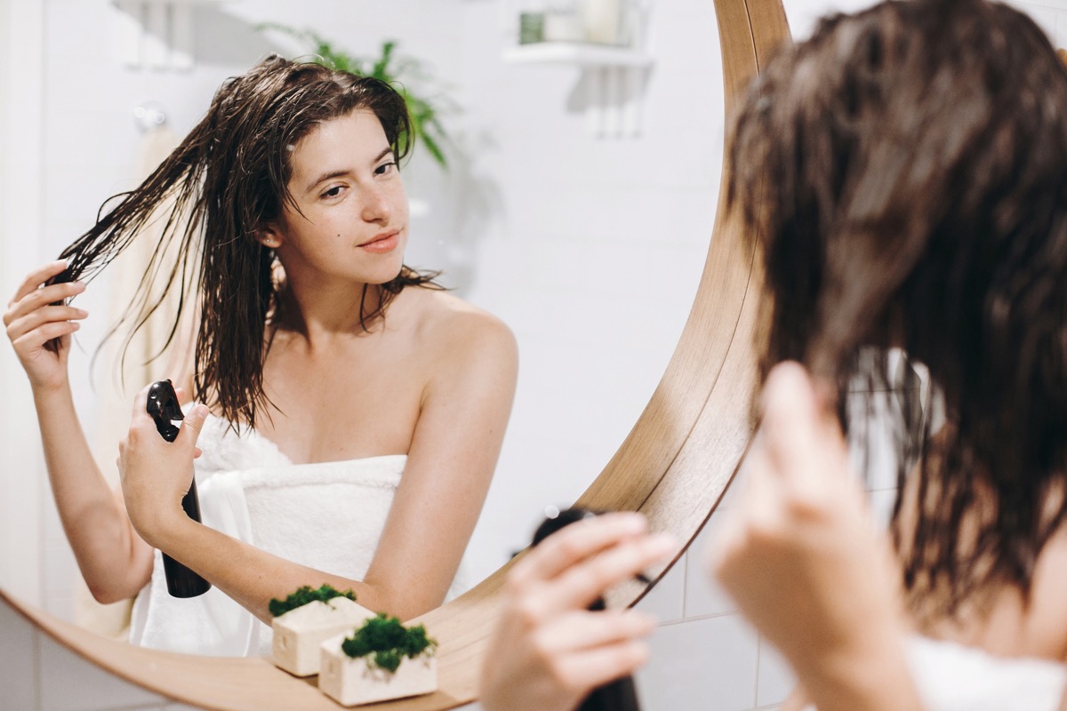 Woman putting product in her hair in front of the mirror in the bathroom
