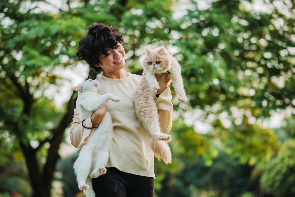 woman holding two cats outside