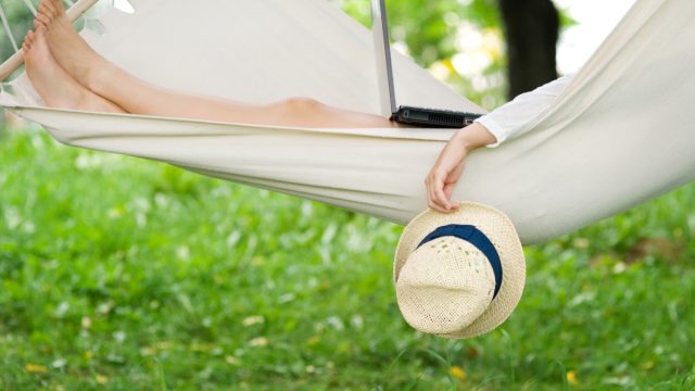 woman relaxing outdoors in hammock with laptop