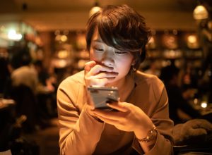 young woman using smart phone in cafe after work
