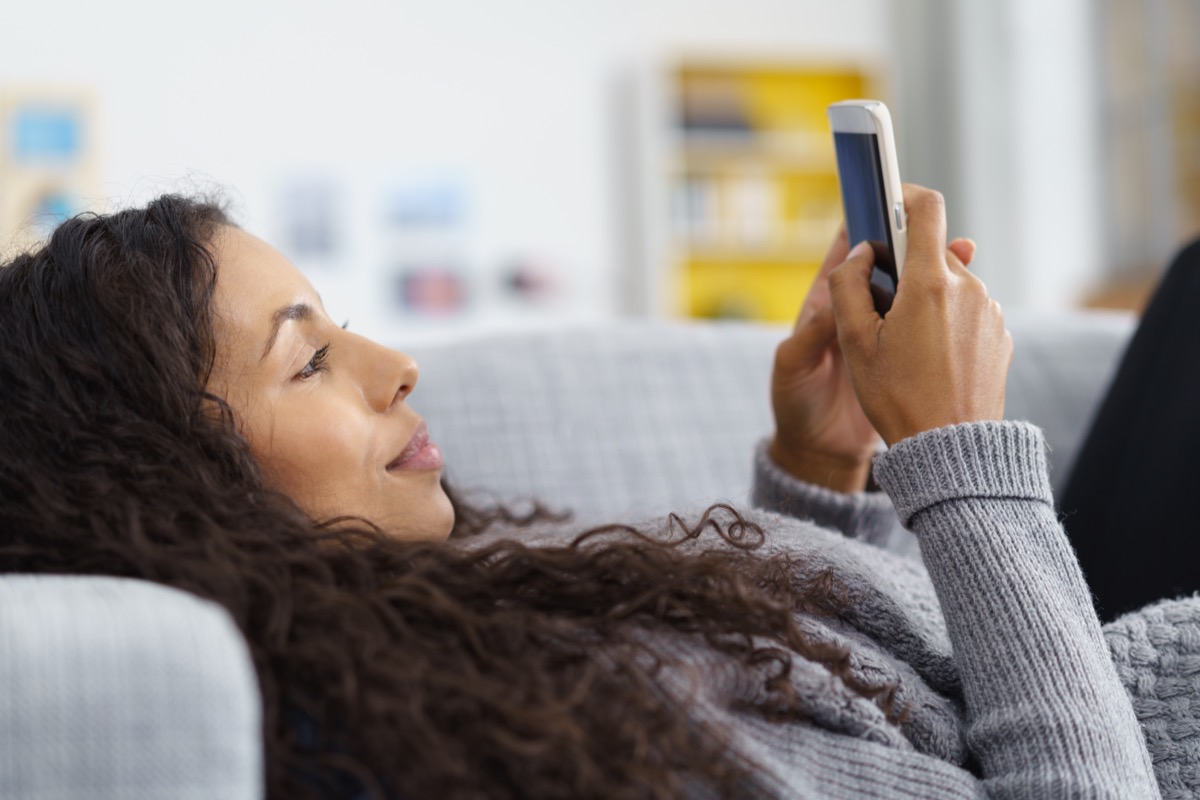 woman texting on a cell phone on the couch