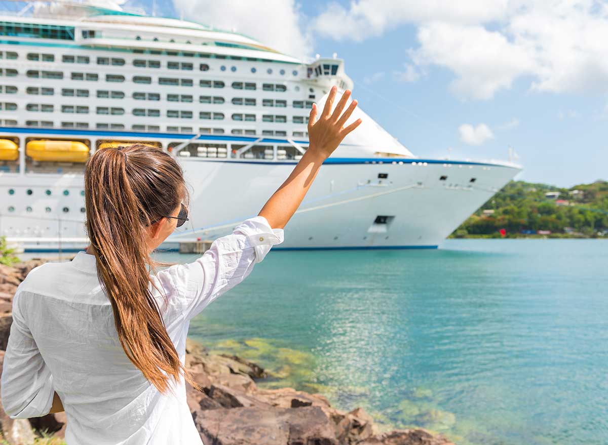young woman waves goodbye to a cruise ship