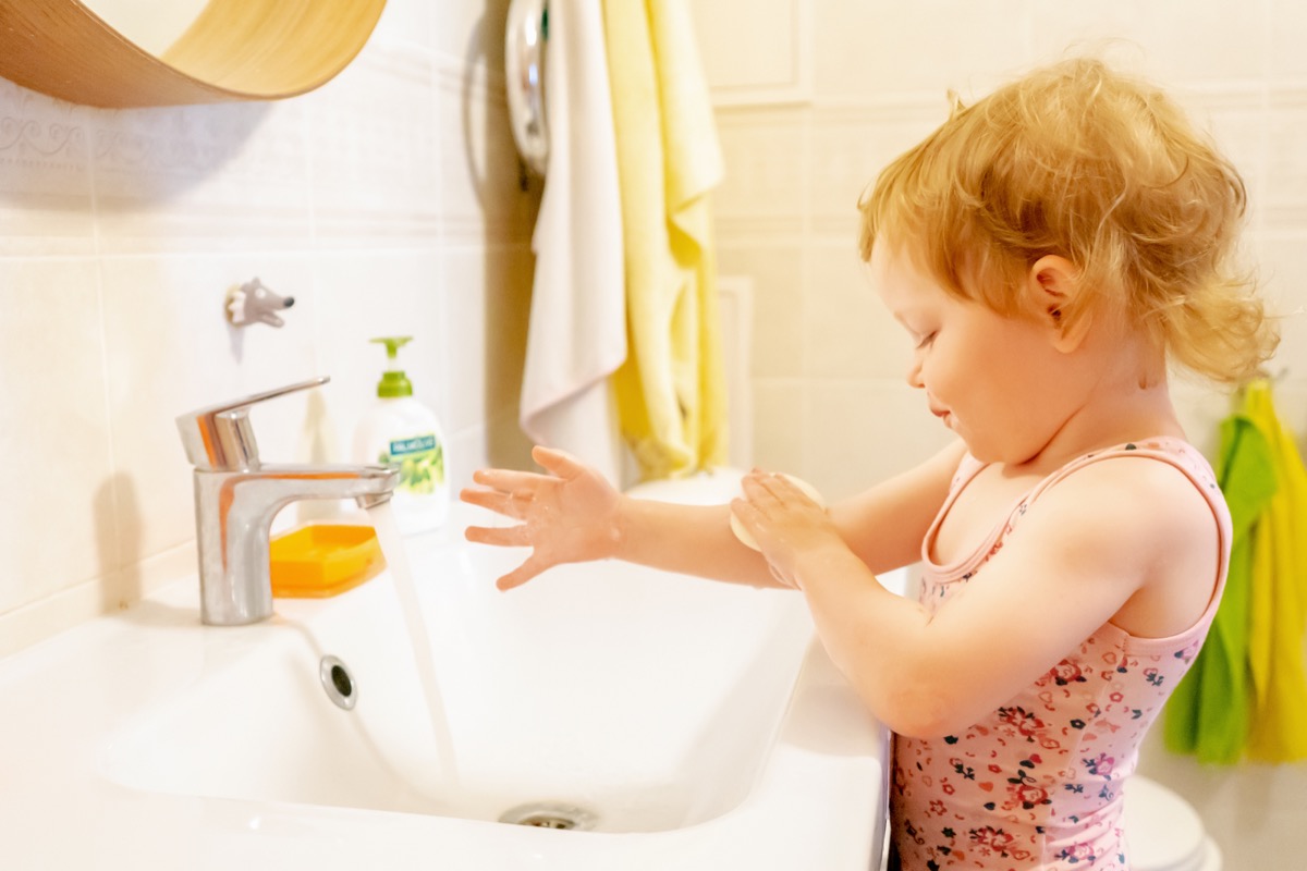 Toddler girl washing her hands in the bathroom sink