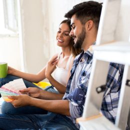 young couple looking at paint samples while sitting on floor