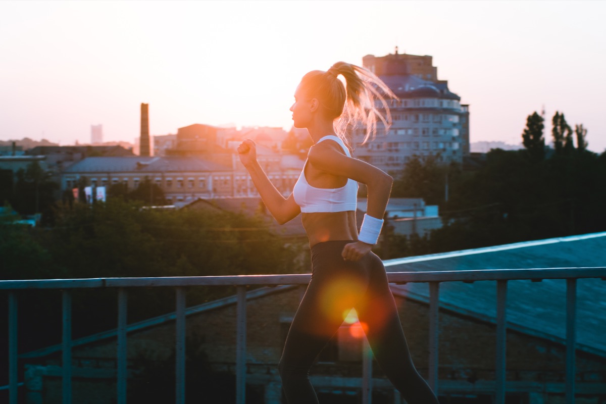 Young woman running at sunrise listening to earphones