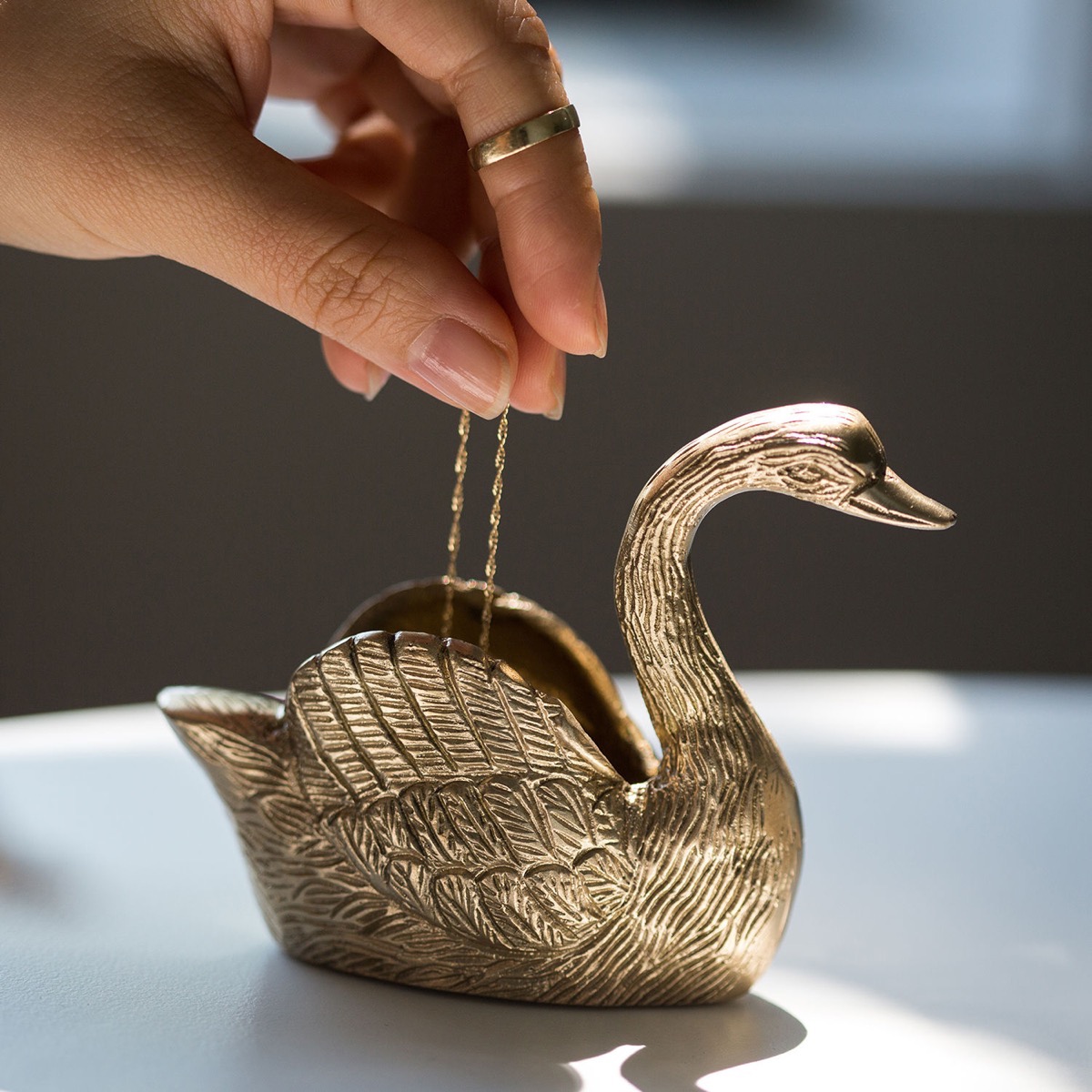 woman putting jewelry in gold swan