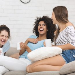 Three young women drinking coffee and laughing
