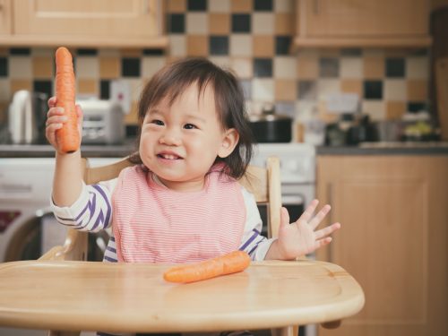 Asiatisches Kind, das eine Karotte hält