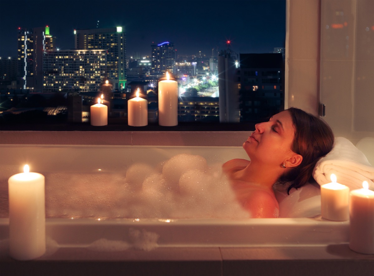 Woman taking a bath with candles and cityscape view