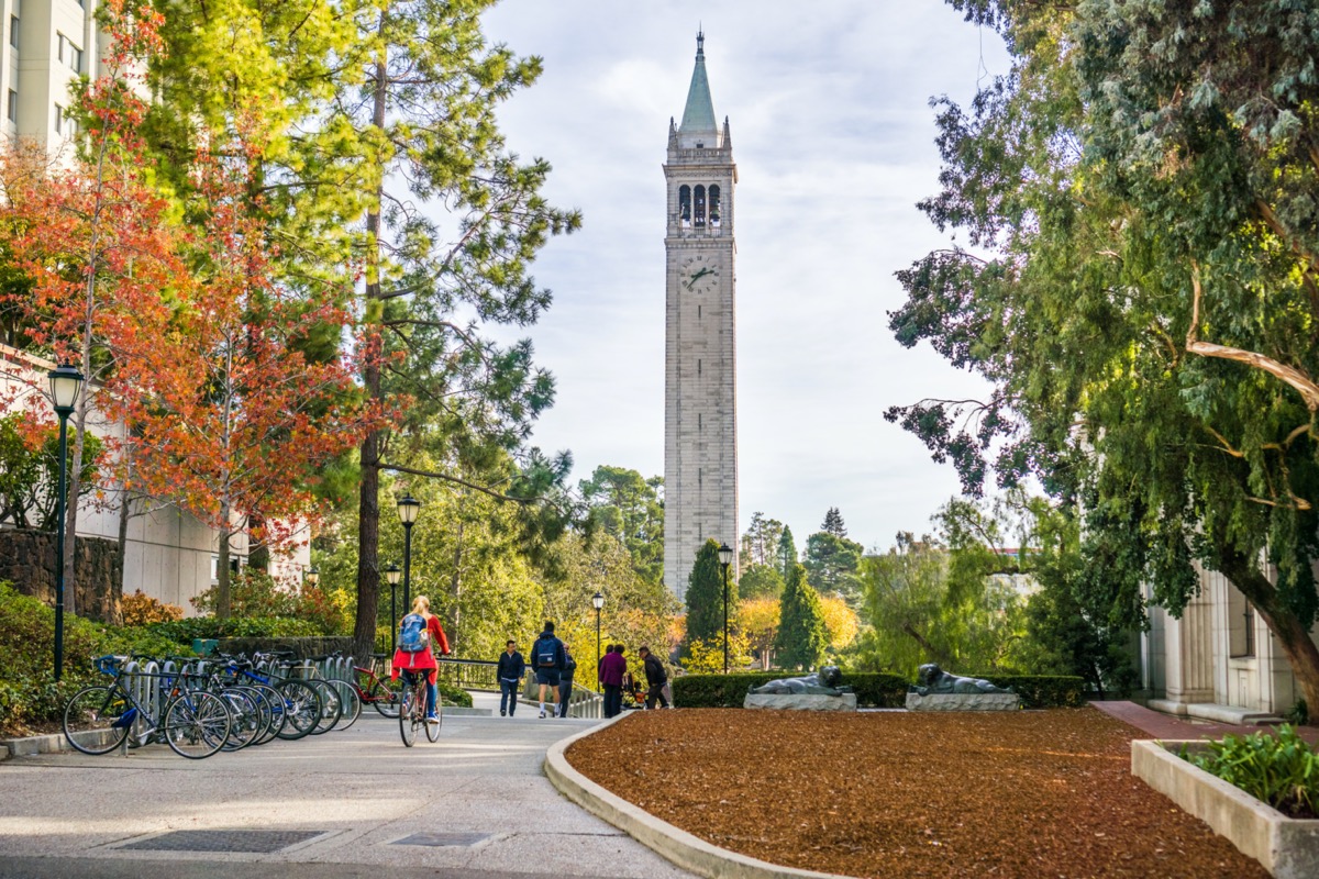 tudents and visitors walking through the campus on a sunny autumn day; Sather Tower in the background