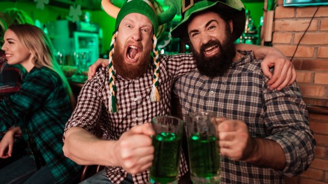 Two men drinking beer in the bar and celebrating St. Patrick's Day