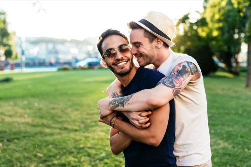 Gay couple spending time together hugging on a park date outside