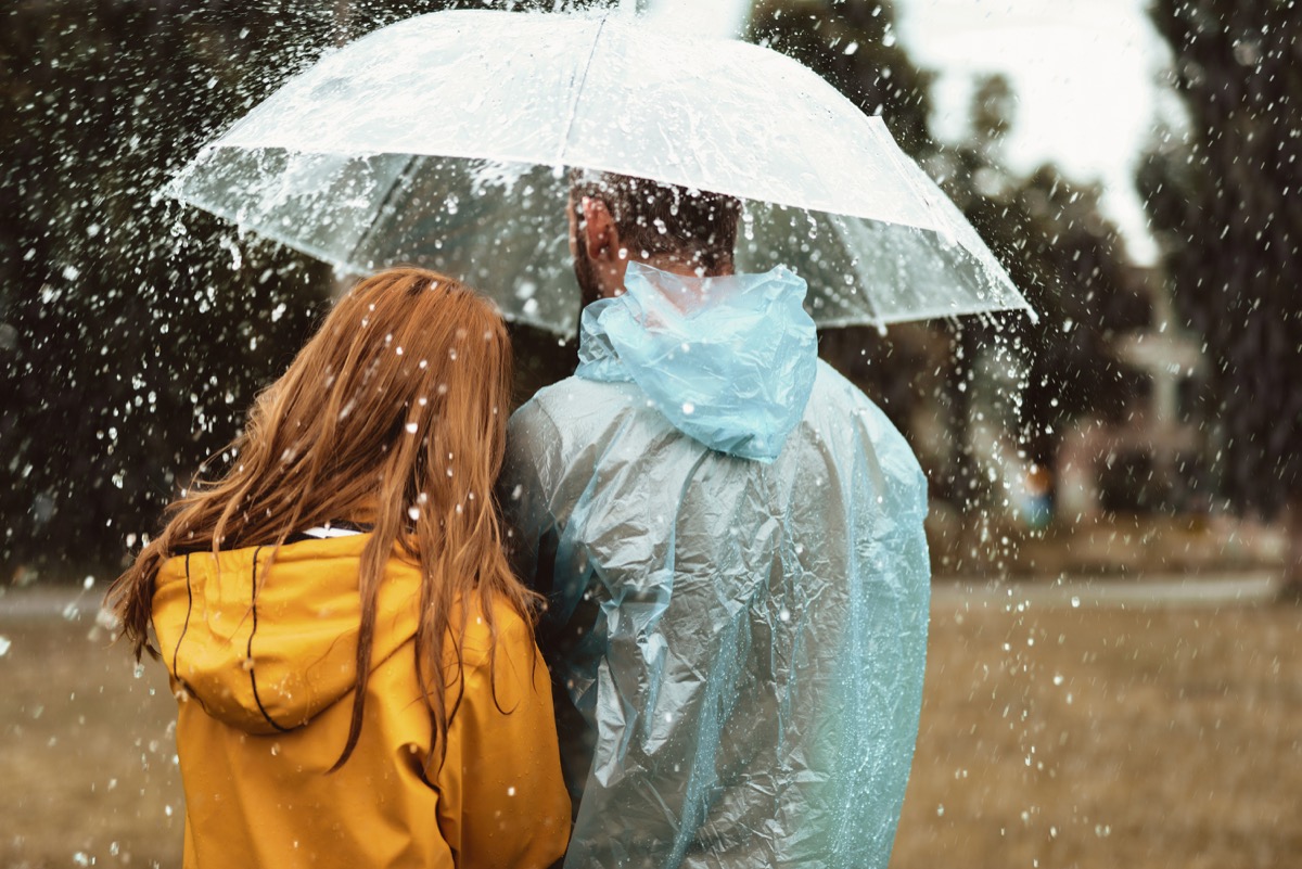 man and woman walking under one umbrella in the rain together
