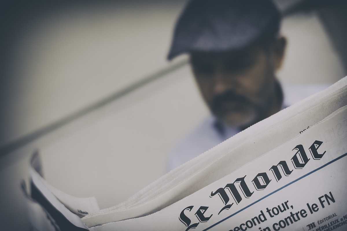 man reading a newspaper with french writing at the top
