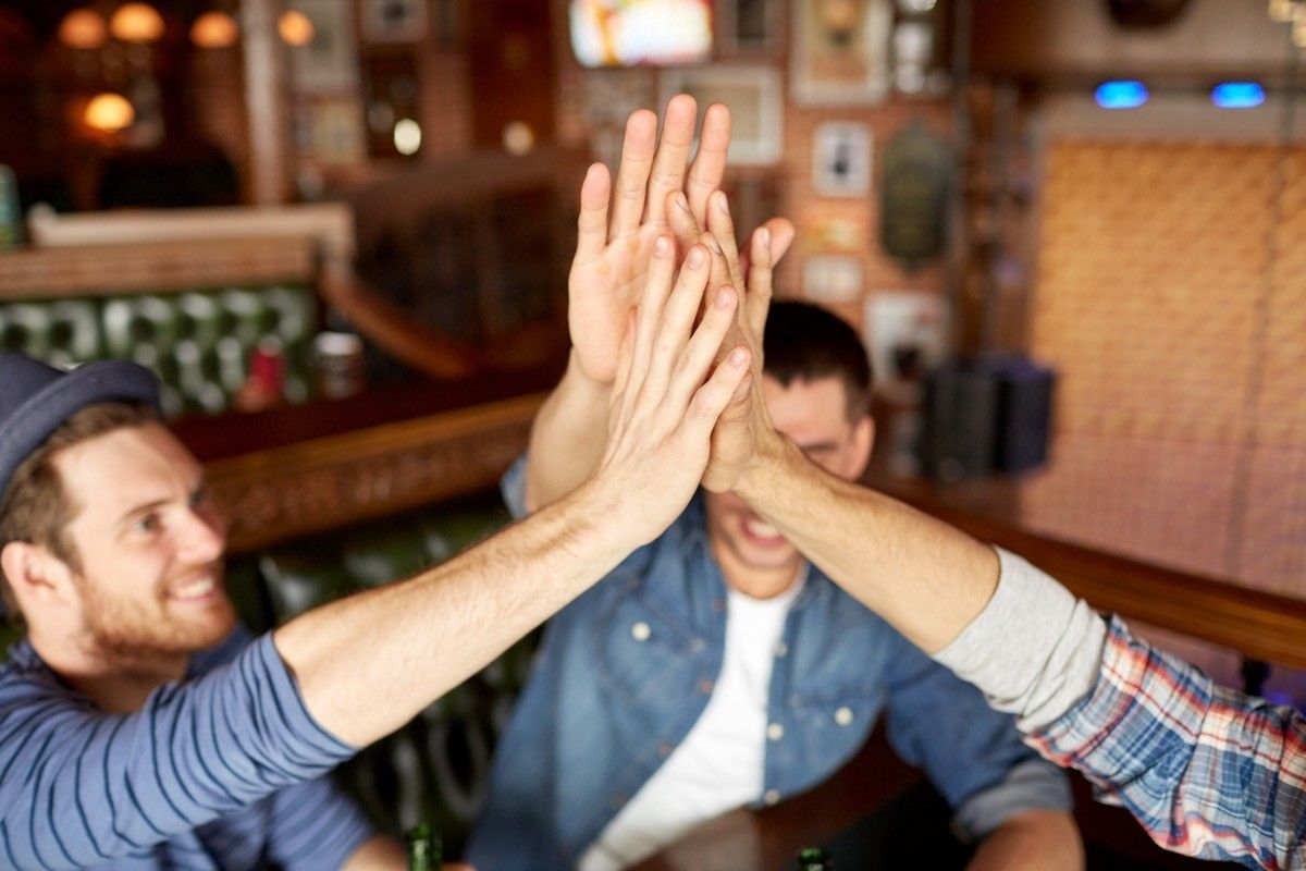 Male friends high-fiving at the bar