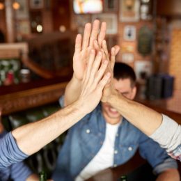 Male friends high-fiving at the bar