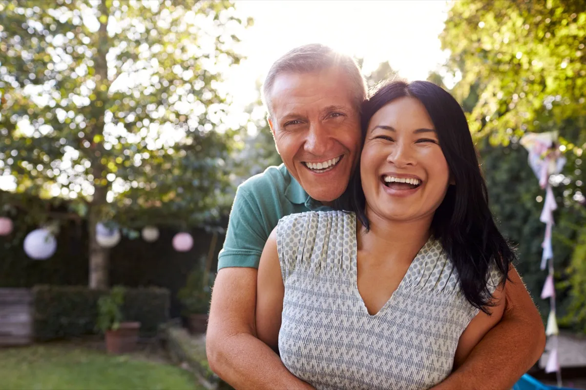happy middle aged asian woman and white man outdoors