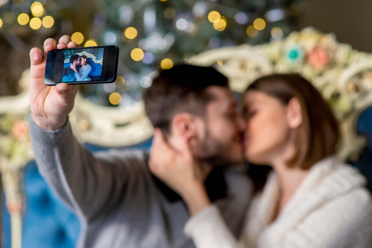 30-something white couple kissing and taking selfie