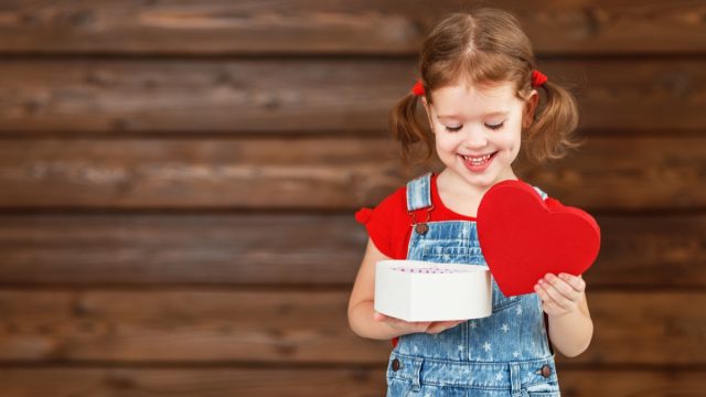 little girl with pigtails opening heart shaped box