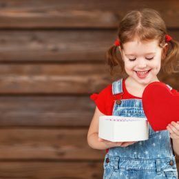 little girl with pigtails opening heart shaped box