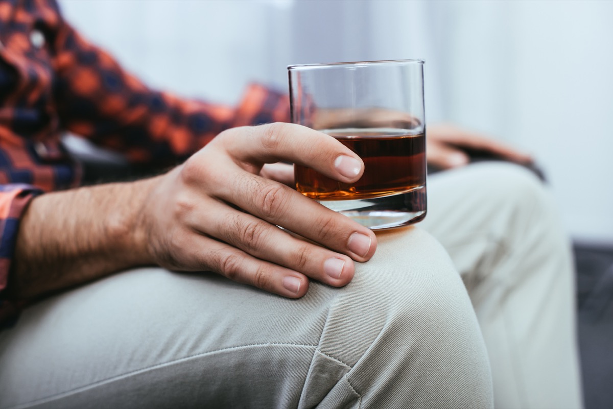 cropped shot of young man holding glass of whiskey