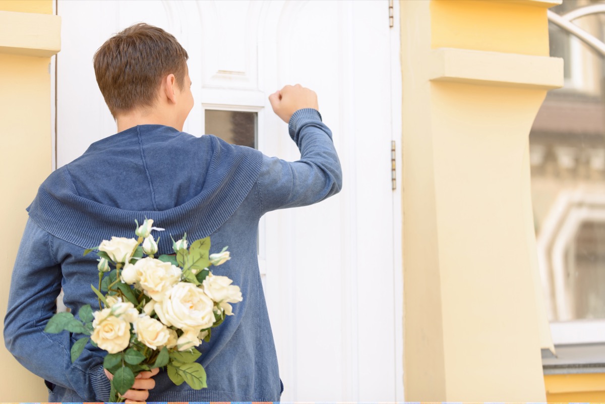 white man standing outside door with flowers