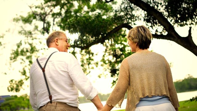 older couple walking hand in hand outdoors