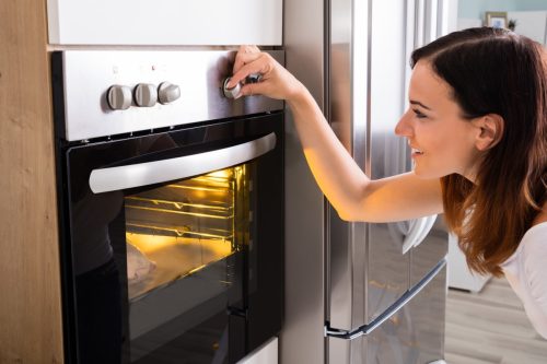 Woman turning dial on oven while cooking