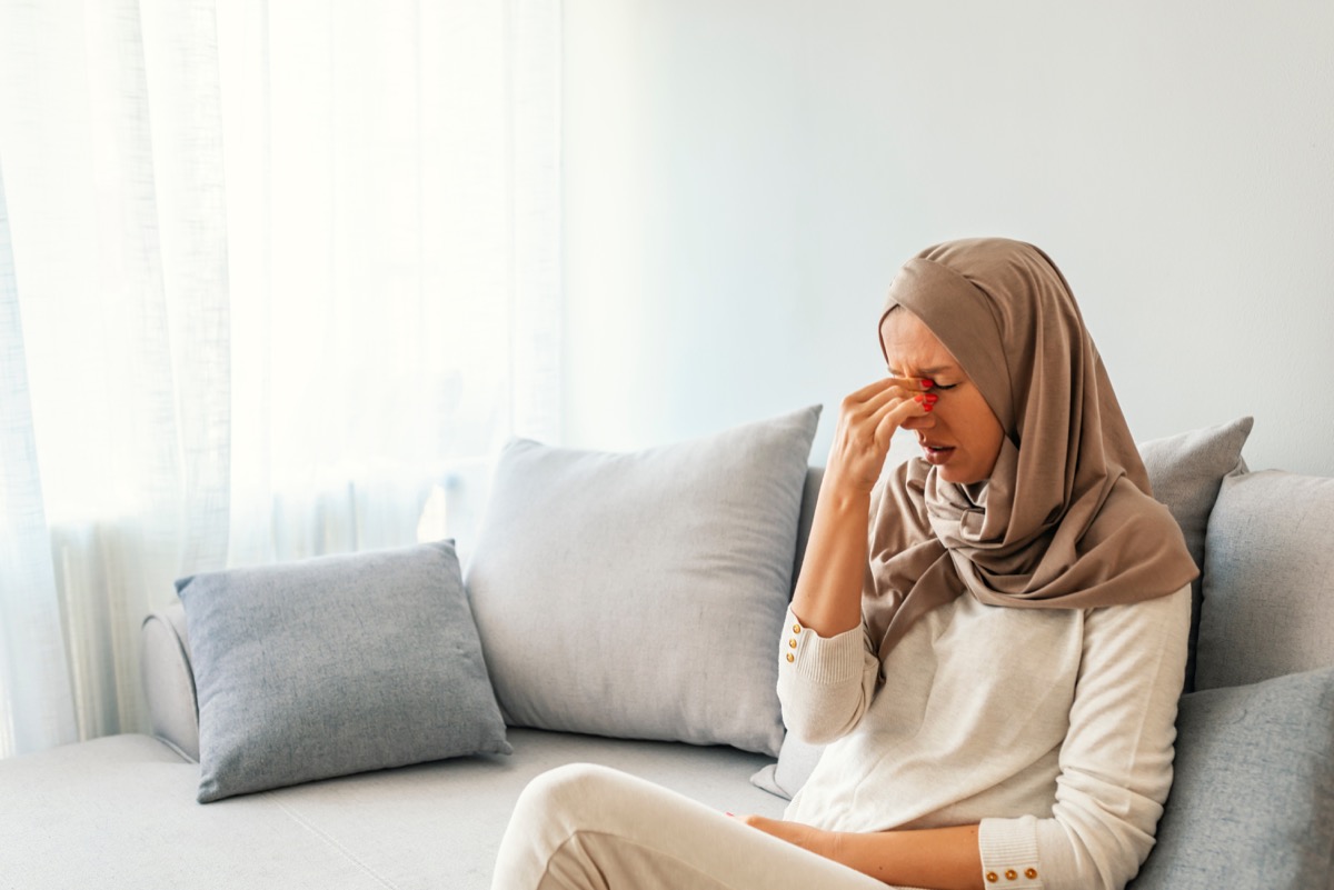 sad muslim woman in hijab on couch