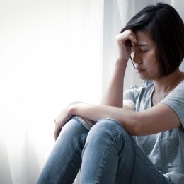 upset middle-aged asian woman sitting on floor