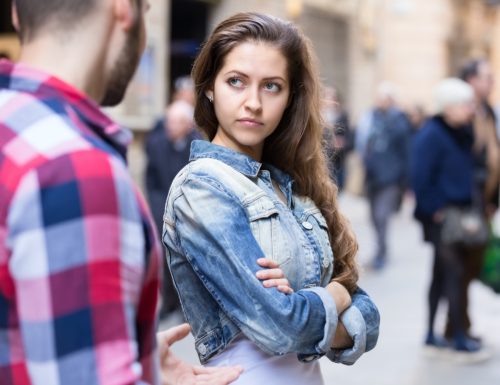 young white woman with crossed arms looking upset at man