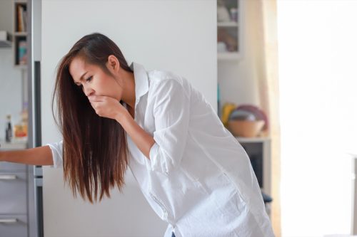 young woman with nausea covering her mouth