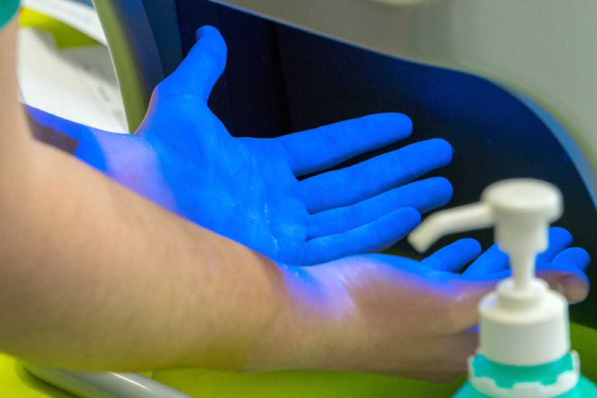 closeup of hands under UV disinfecting lamp