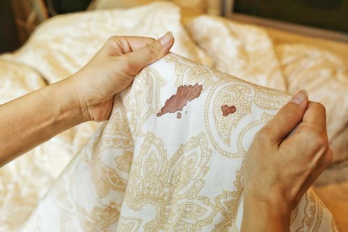 woman holding bed sheets with blood stains