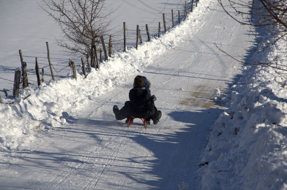 boy sledding down a snowy road