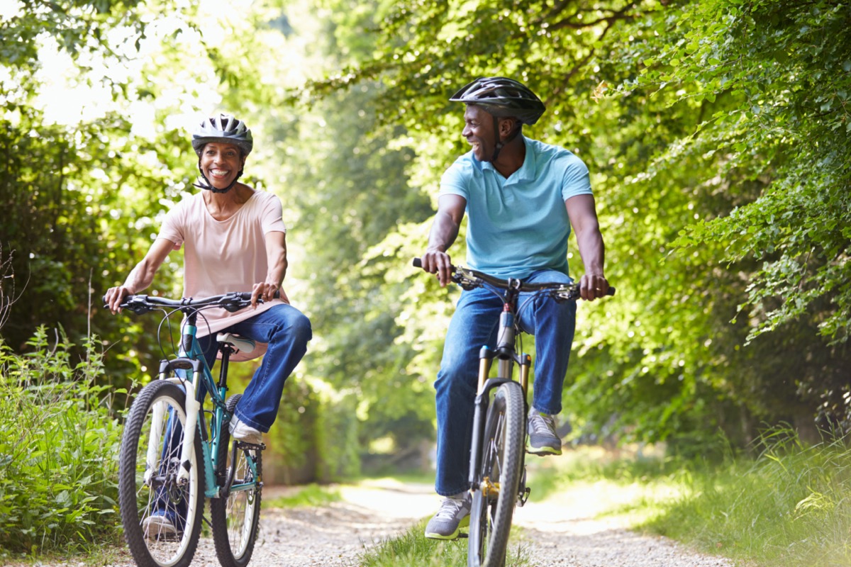 mature black woman in pink shirt and man in blue shirt riding bikes