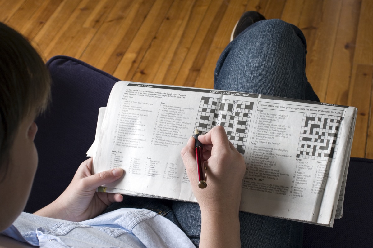 Person doing a crossword puzzle in the newspaper