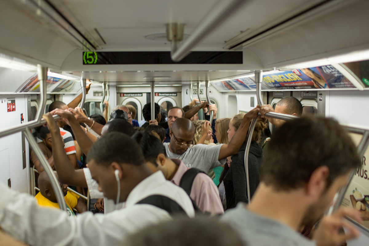 crowded new york city subway shows people holding on to bar