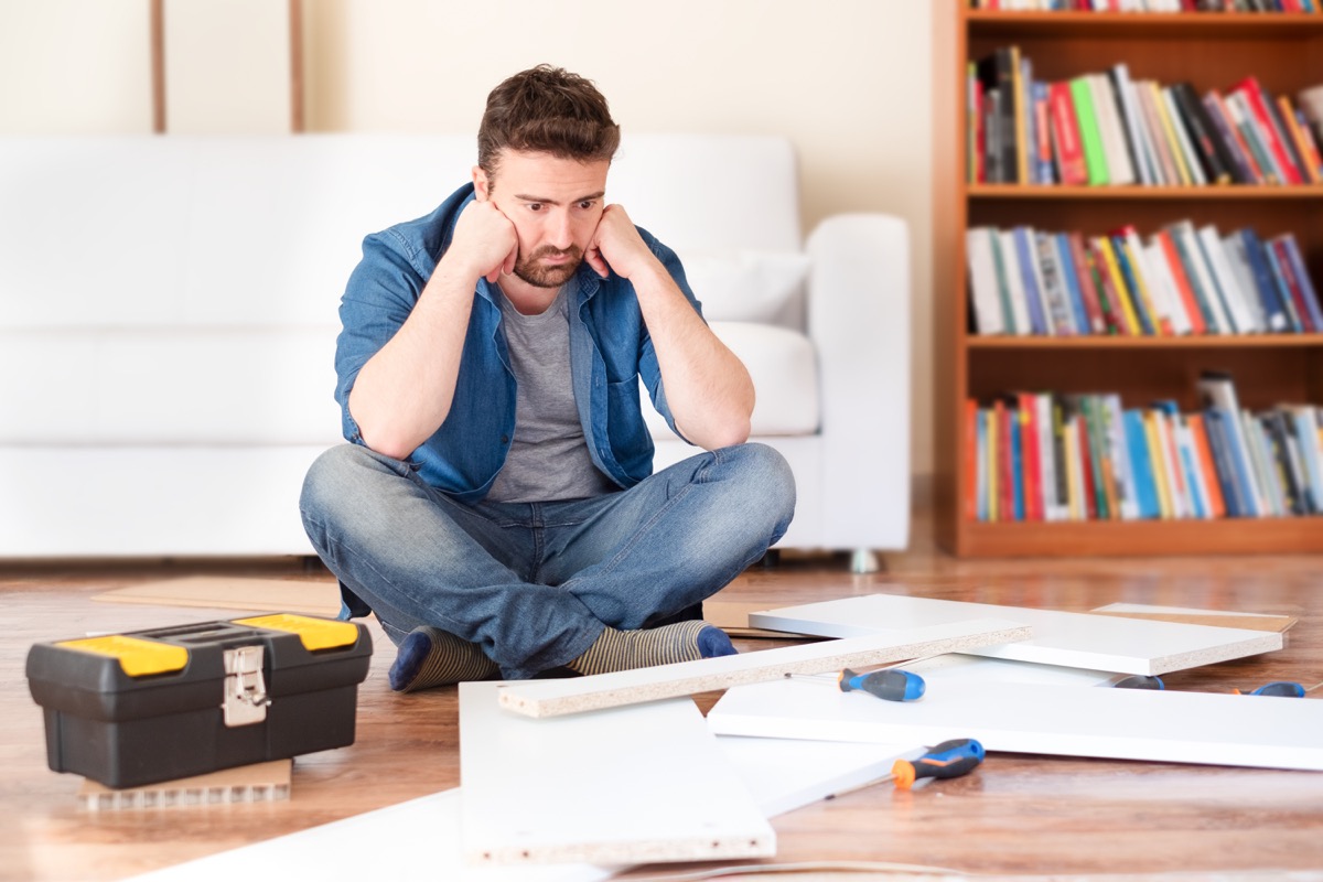 Man putting together DIY furniture frustrated doesn't know what he is doing