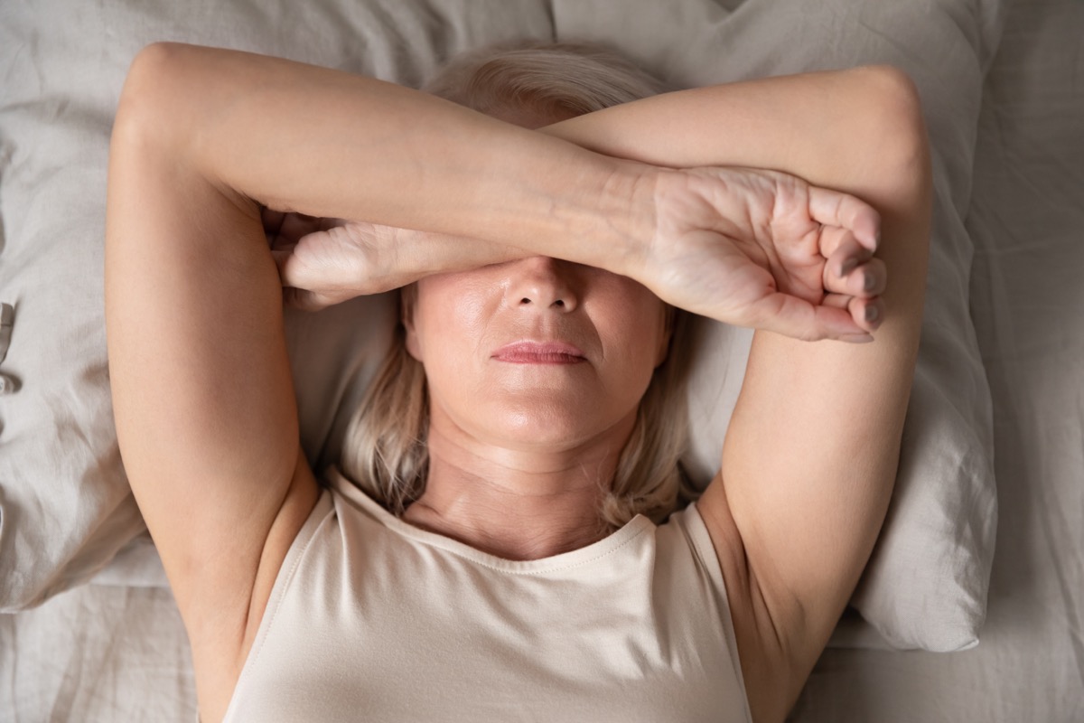 Older woman drained laying in bed tired
