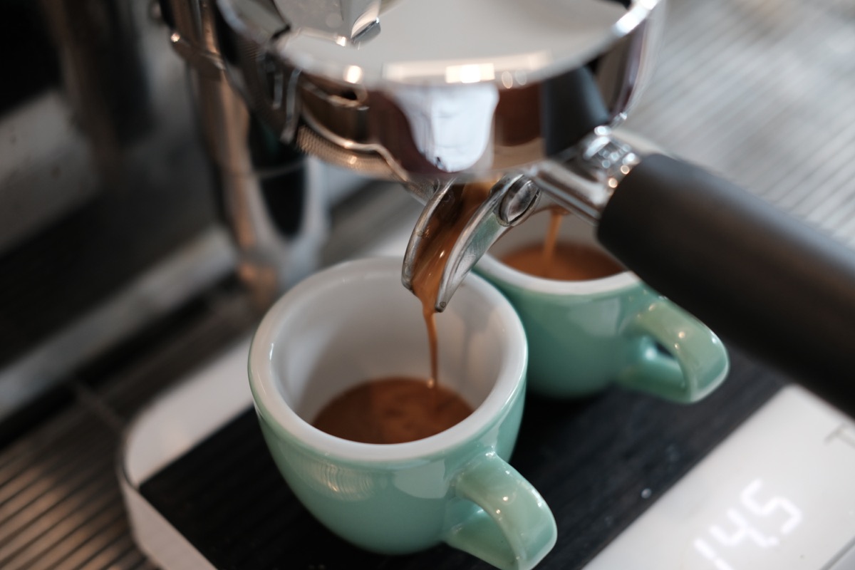 Espresso machine extracting coffee into tiny cups