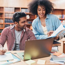 friend explaining book to classmate in library