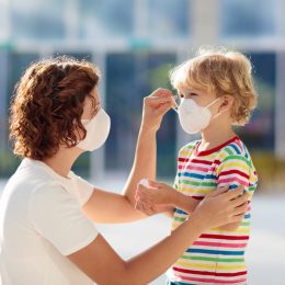 Mother putting a face mask on her child's face