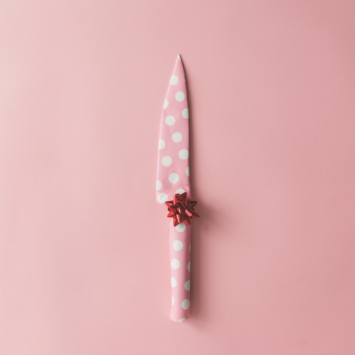 gift wrapped knife on pink background